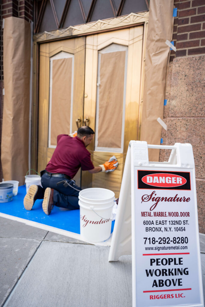 Signature metal employee working on door restoration on building in NYC