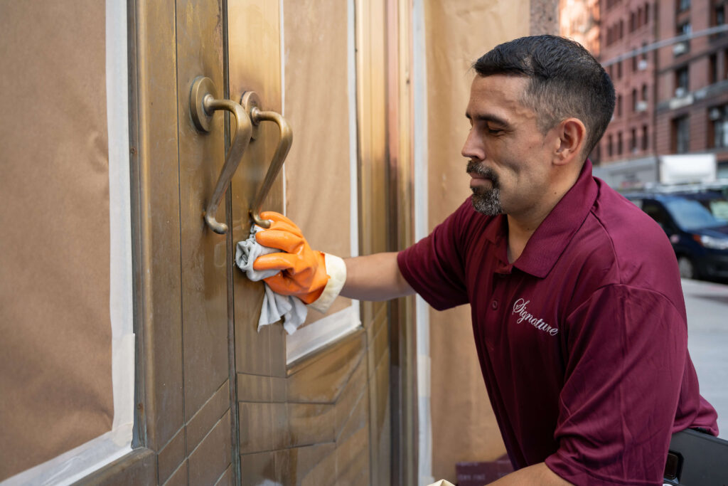 man in Signature red shirt working on door restoration and maintenance