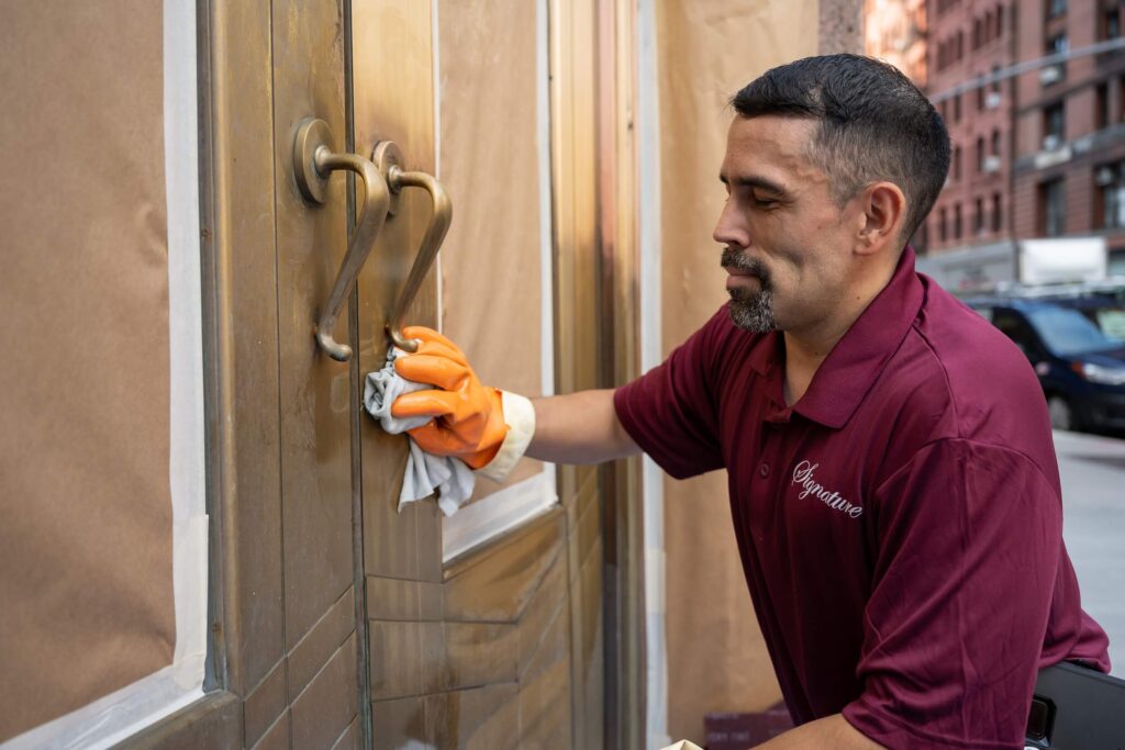 Man in Signature shirt working on metal and door restoration