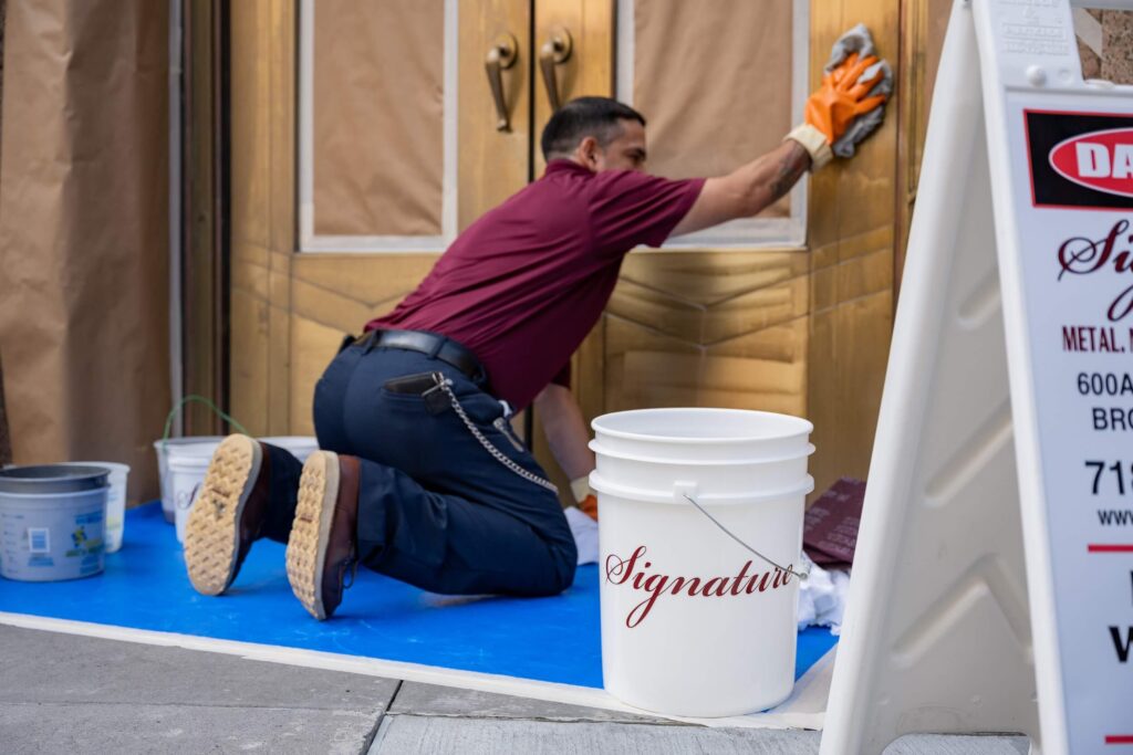 Man in Signature shirt working on metal and door restoration