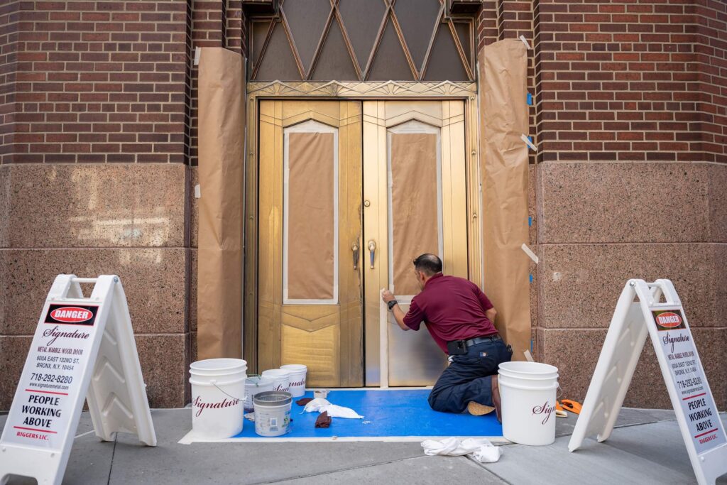 Man in Signature shirt working on metal and door restoration