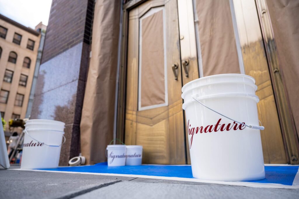 Signature white bucket outside historic building with metal doors and stone, restoration and maintenance services by Signature Metal, New York
