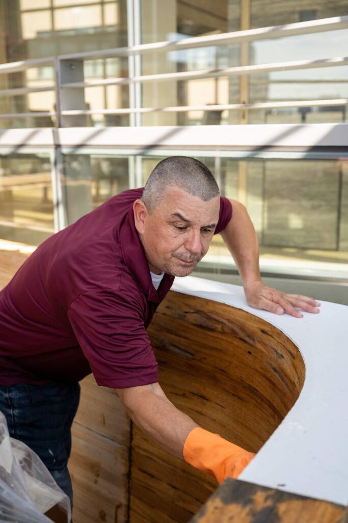 Man in Signature Metal shirt working on wood restoration on rooftop of NYC building