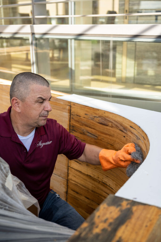 man in Signature red shirt working on Wood restoration and maintenance