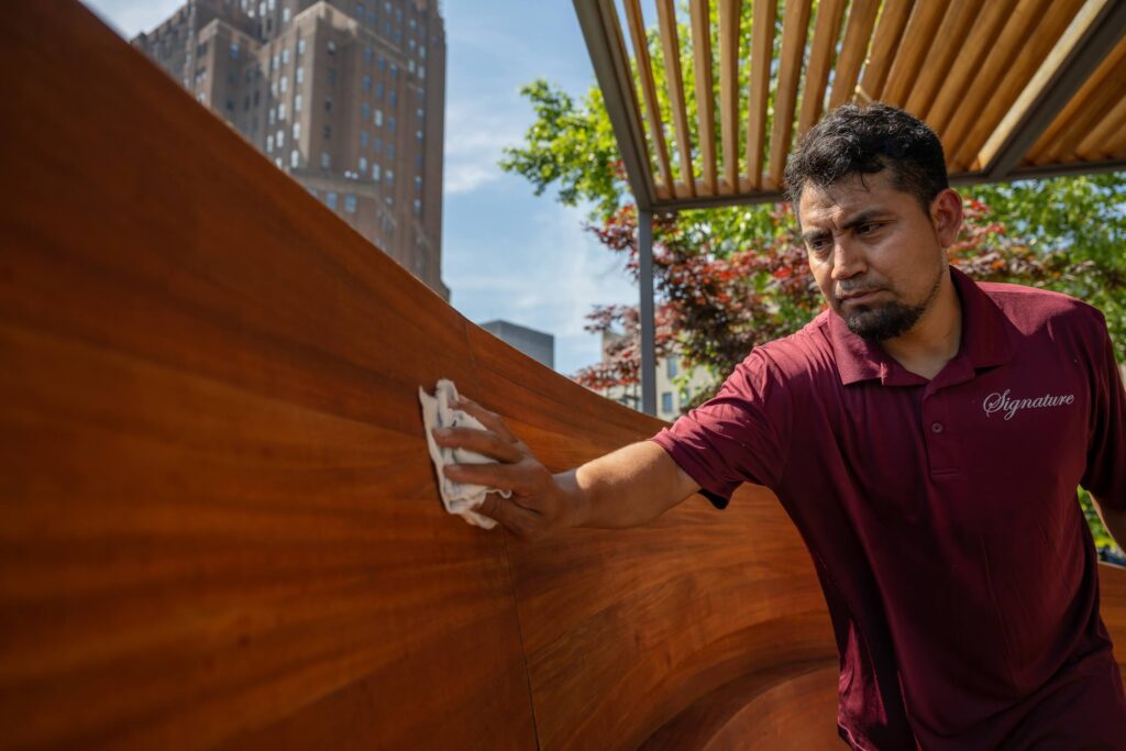 Man in Signature Metal shirt working on wood restoration on rooftop of NYC building